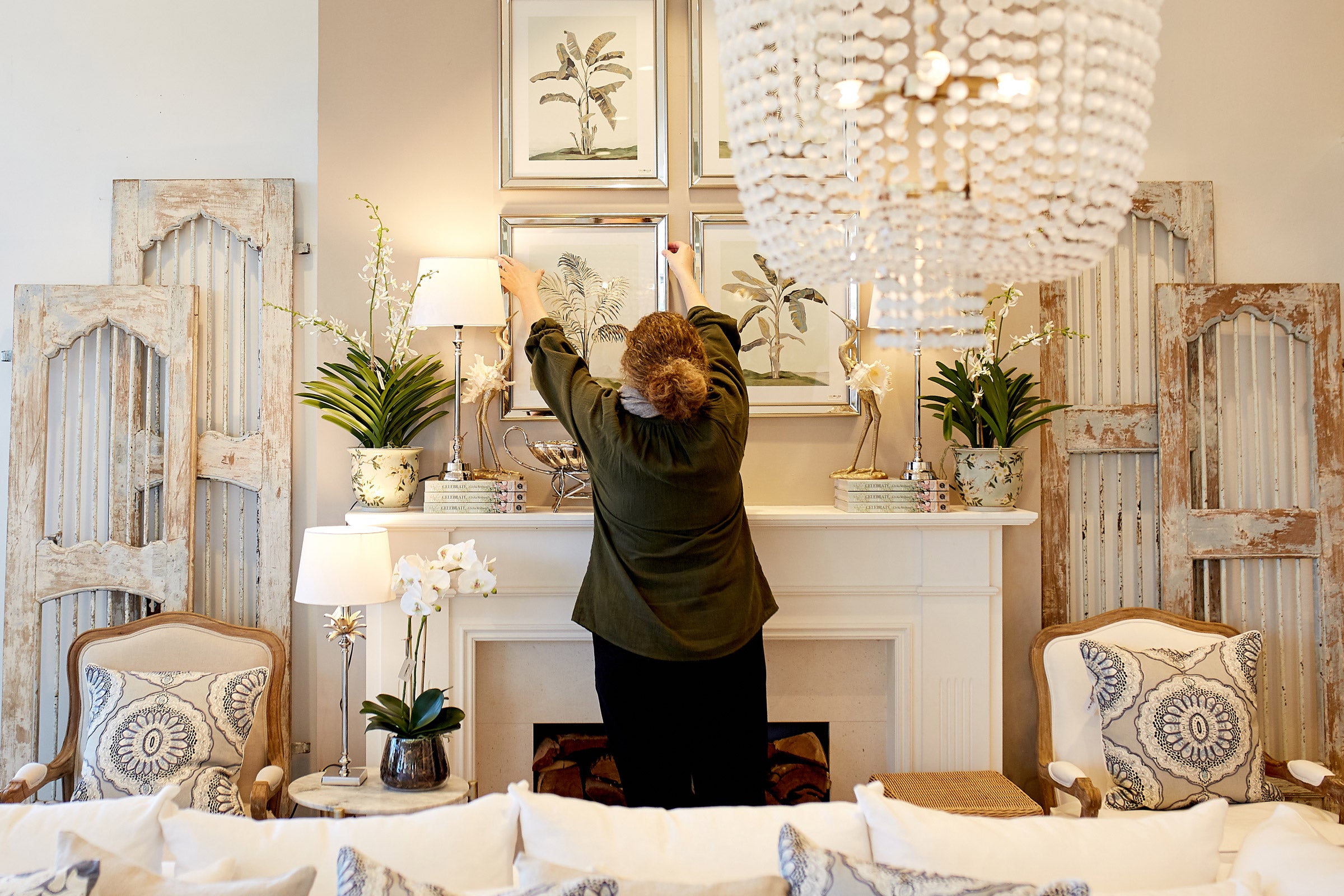 Our in-store visual merchandiser adjusting a display of prints above a mantle.
