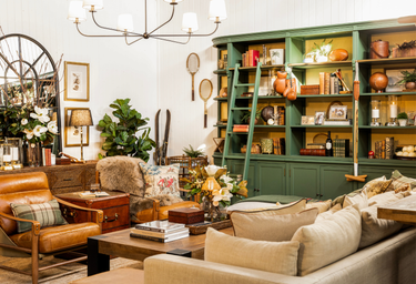 Heritage inspired living room with a green bookshelf, brown leather chair, and beige sofa,