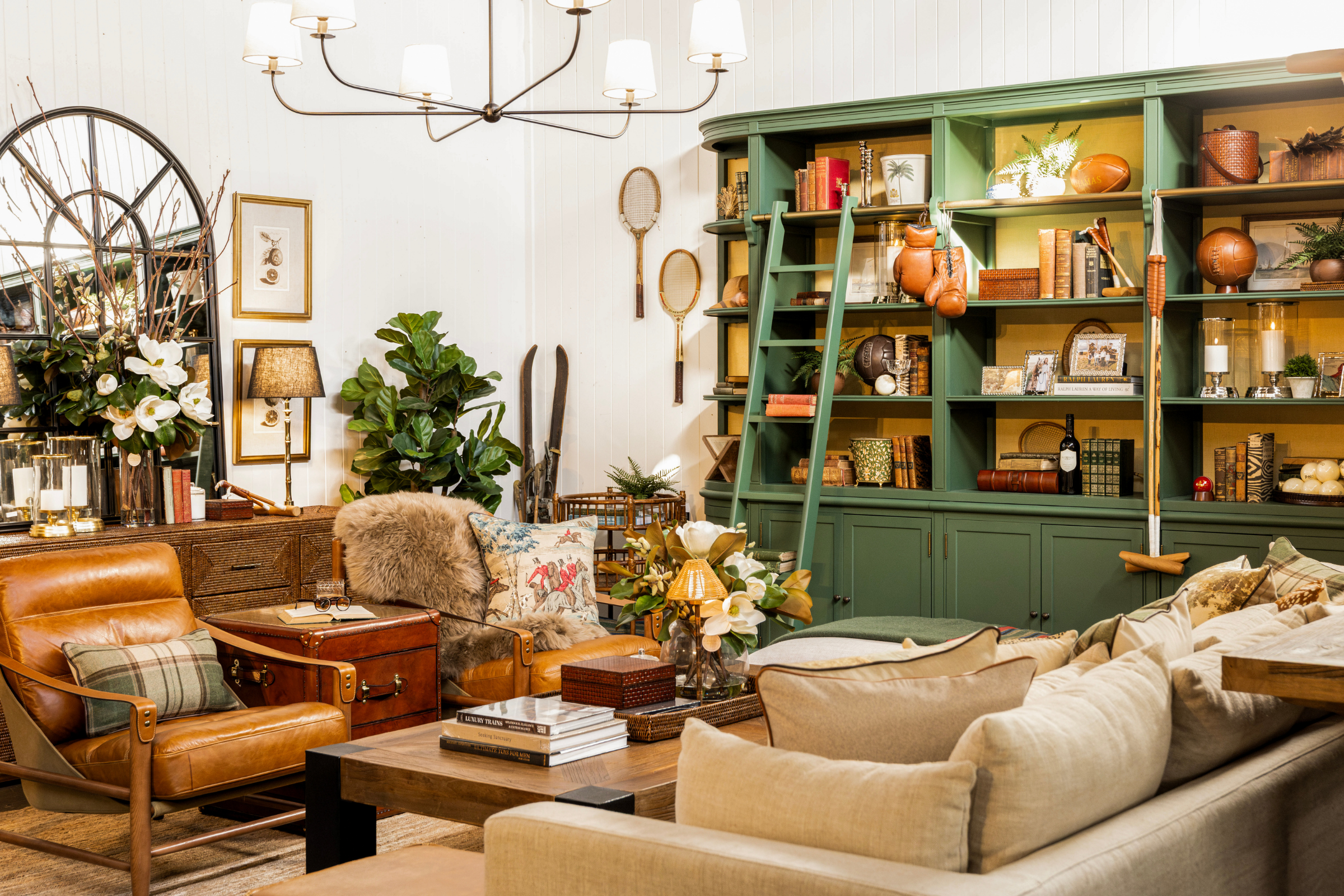 Heritage inspired living room with brown leather chair, beige sofa, and green bookshelf.