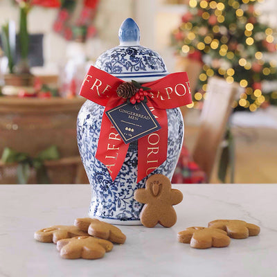 Decorative gingerbread jar with gingerbread men on a table, Christmas tree in the background
