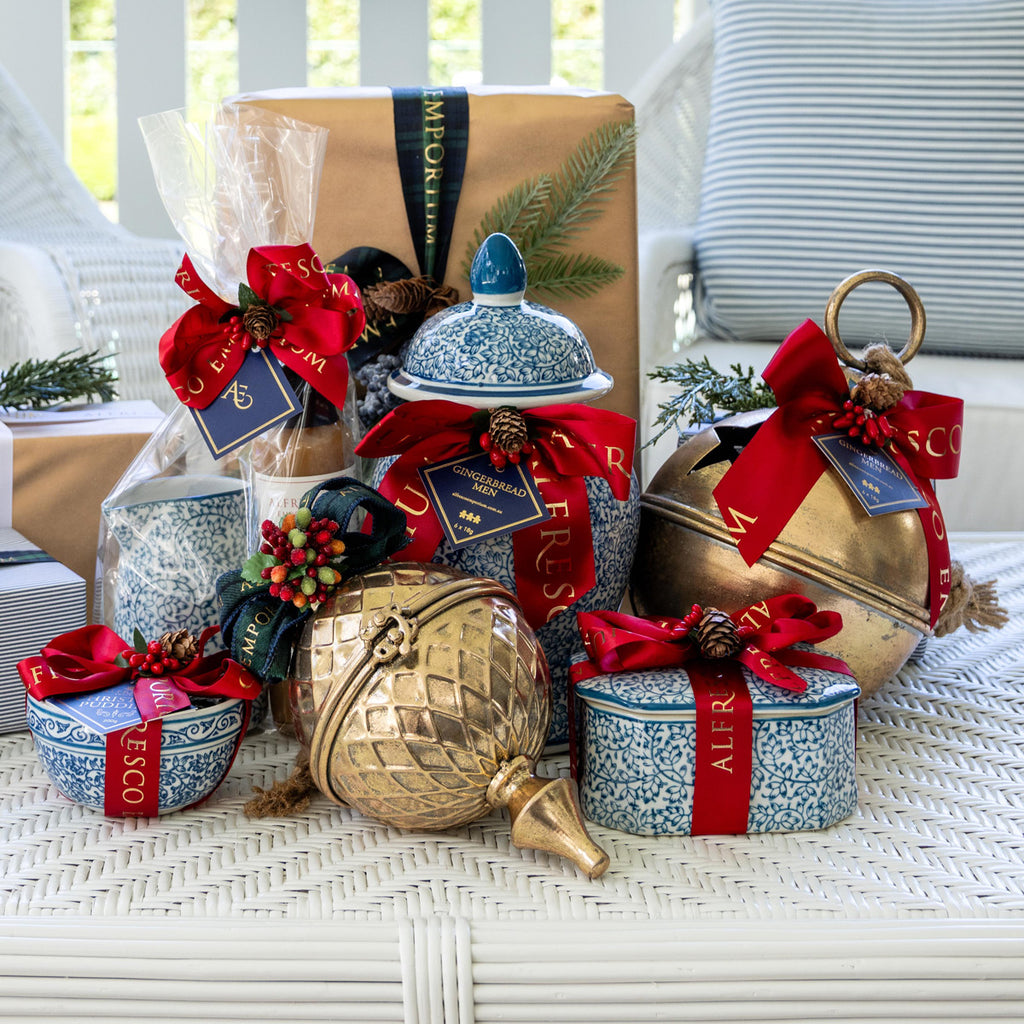 The Alfresco Emporium 2026 Gifting Collection of gold metal baubles and blue and white ceramic jars filled with treats.