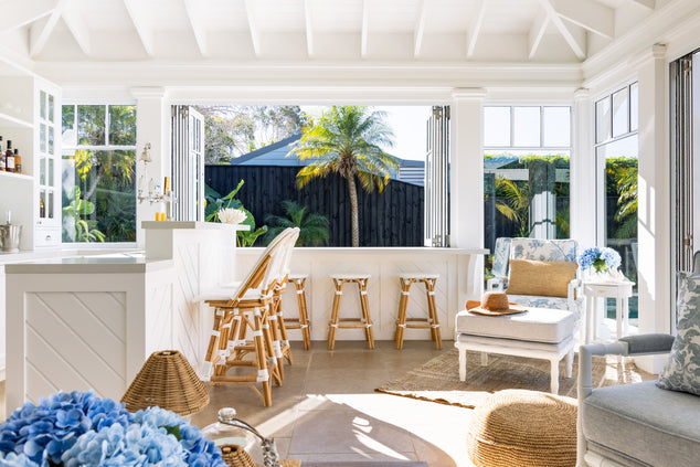 Pool House styled with St Tropez bar stools with an Indira arm chair and foot stool in the corner