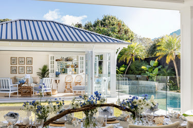 Overview of Coastal Collection Featuring Outdoor Dining Table with Pool house including three Indira Chairs and Indira ottoman and two Antigua bar stools.