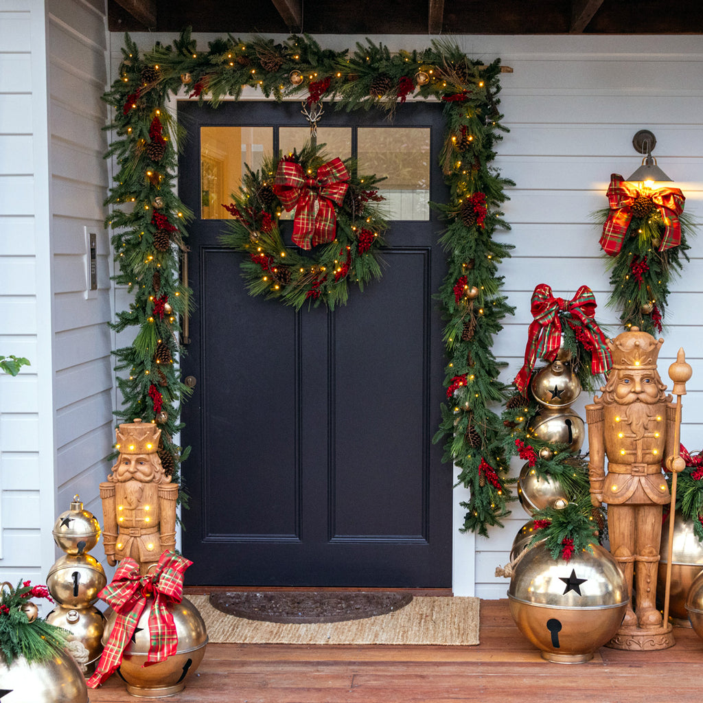 Decorative Christmas front door with Colorado Red Berry wreath, red berry garlands, oversized star bell ornaments and giant timber-look nutcrackers.