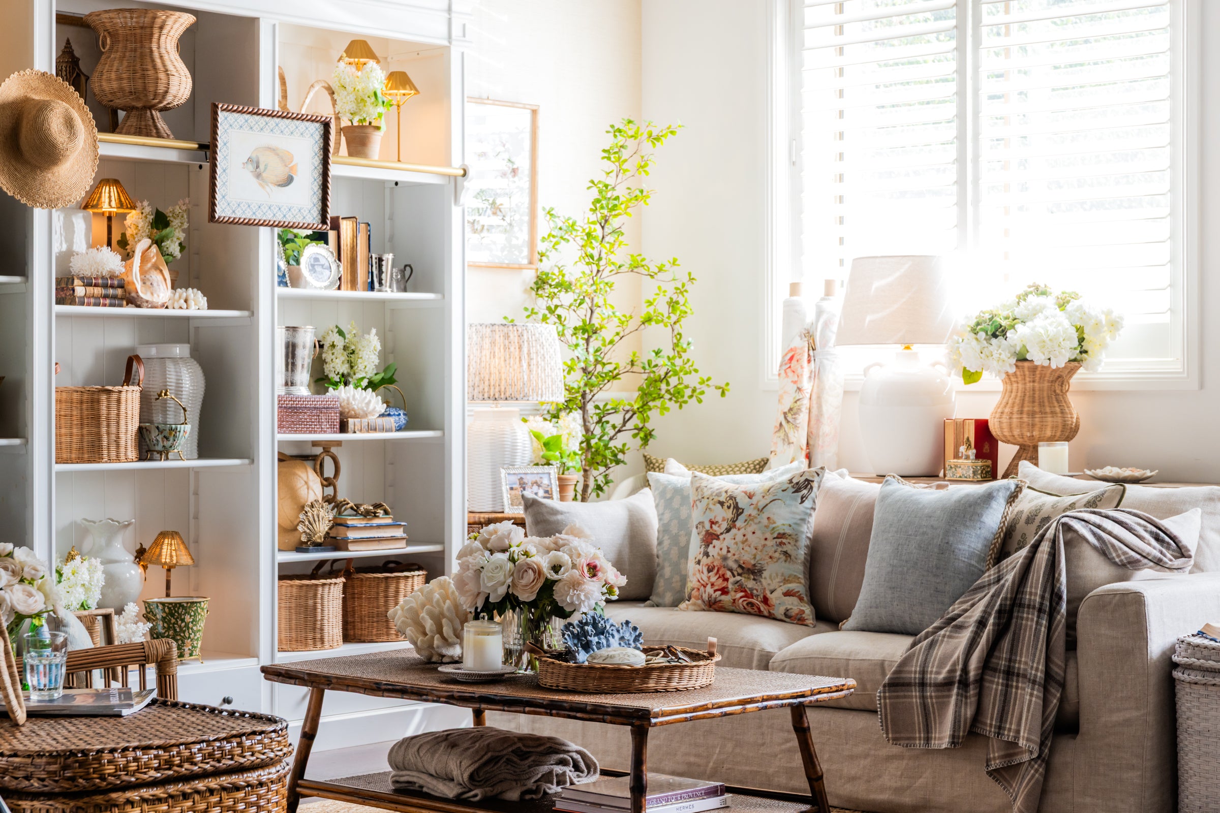 English Coastal living room with floral cushions on sofa, and variety of decor on bookshelf