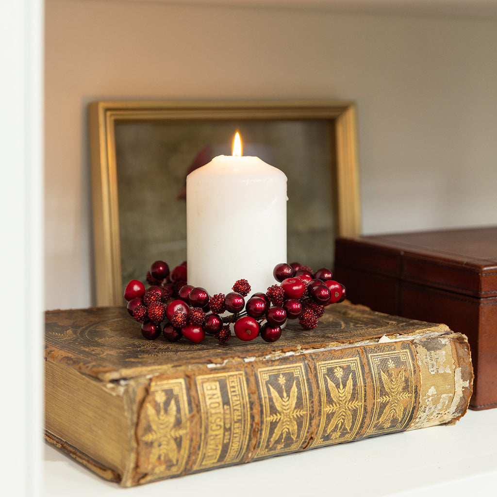 Red berry candle ring with white candle styled on a vintage book.