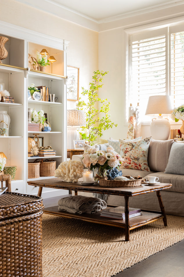 English Coastal living room with floral cushions on sofa, and variety of decor on bookshelf