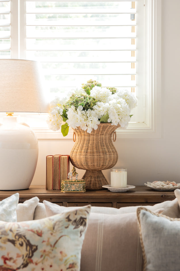 Console with Rattan vase and hydrangeas and books and barclay gift box 
