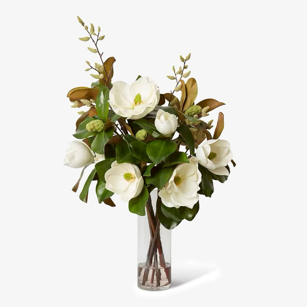 Bouquet of white flowers with green leaves in a clear vase on a white background