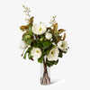 Bouquet of white flowers with green leaves in a clear vase on a white background