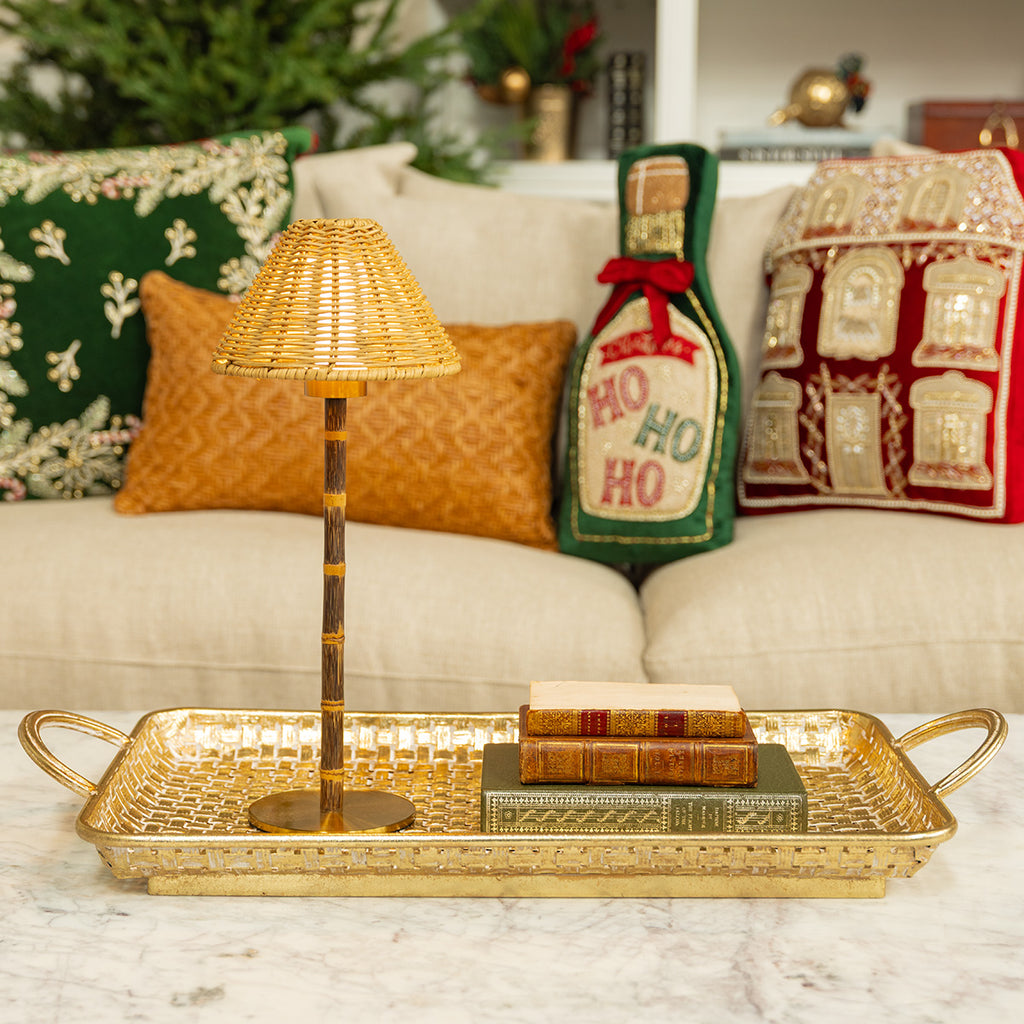 A gold tray with a cordless lamp and books styled on it.