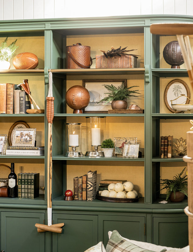 Green bookshelf with decorative items including books, plants, and a sporting equipment.