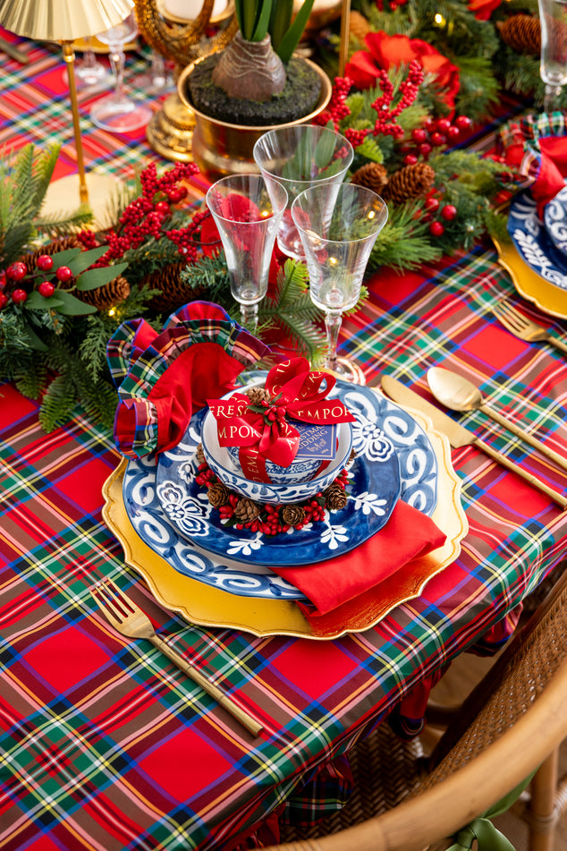 Decorative Christmas table setting with plaid tablecloth, red napkins, and festive decorations.