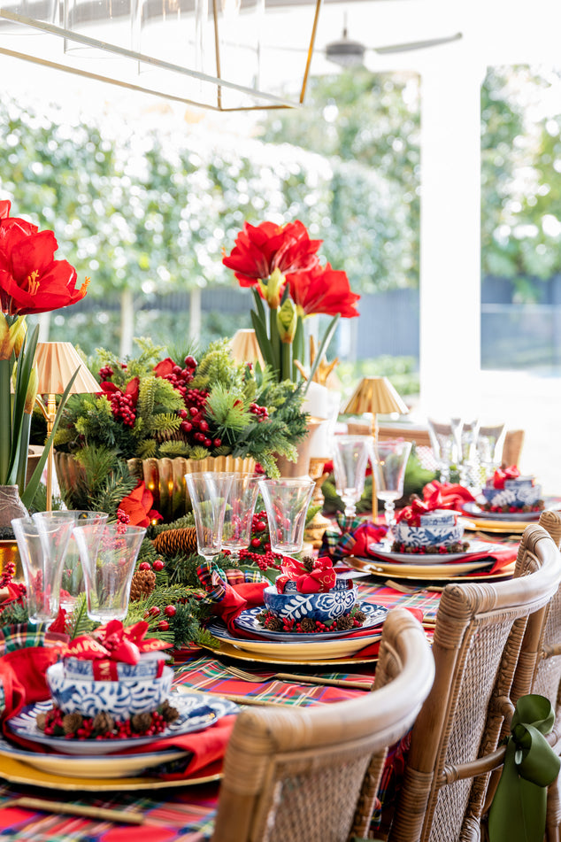Decorated Christmas table with red flowers and festive tableware.