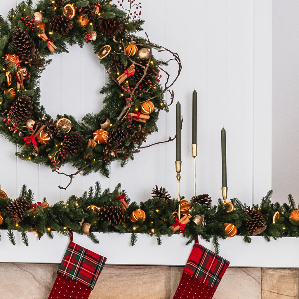 Gold tapered candles on a mantle decorated for Christmas