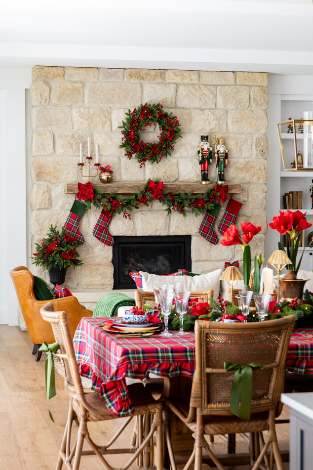 Dining room with Christmas decorations, including a wreath and stockings on a stone fireplace.