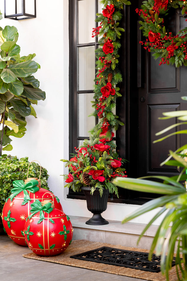 Door Decorated with Red and Green Christmas Wreath and Garland And Flower Arrangement out front with Oversized Red and Green Baubles