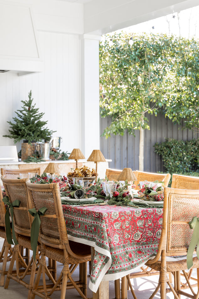 Christmas Dining Table with Festive Rose Tablecloth and Green and Red acvents, Brown Antigua chairs with Green Ribbons