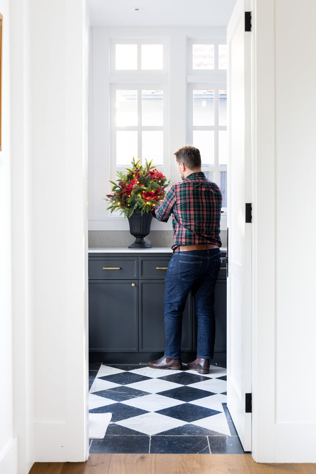 Man arranging Christmas flowers in a laundry with black and white checkered floor
