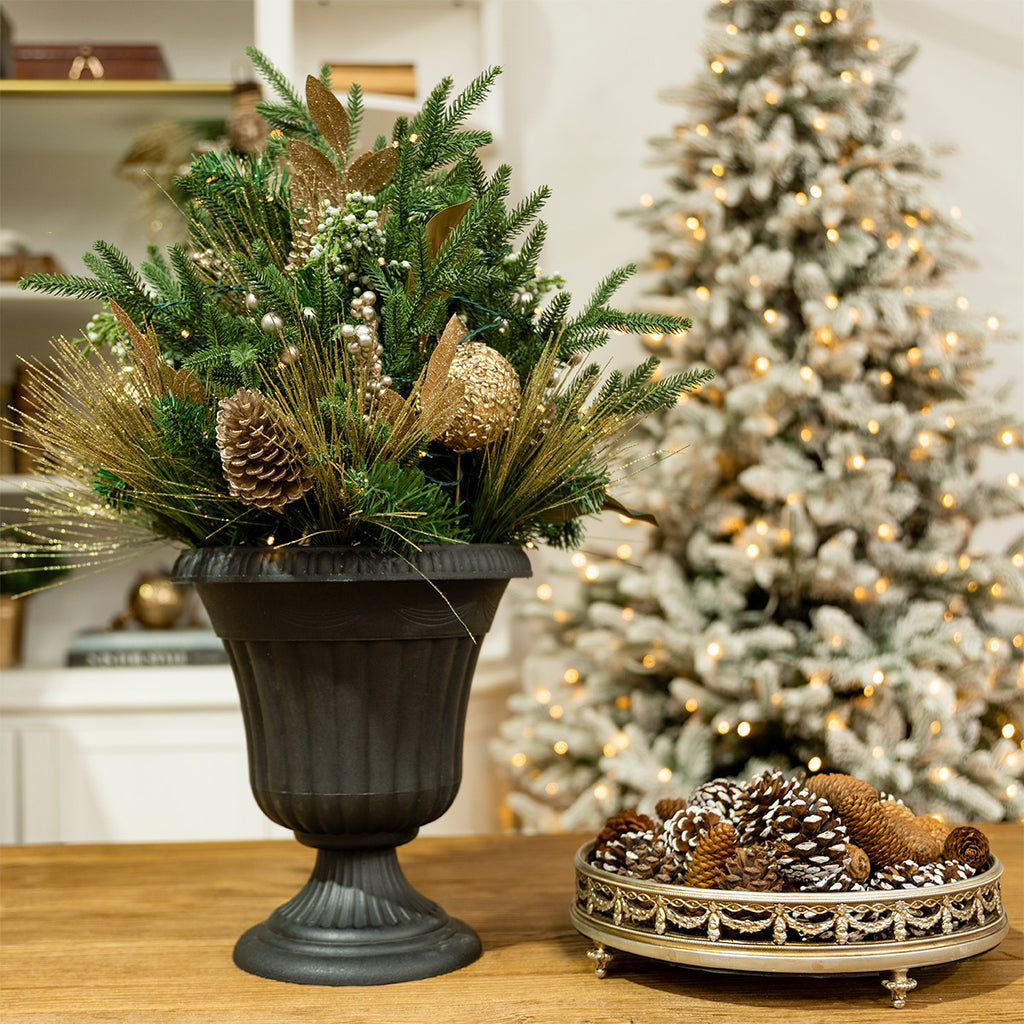 A potted metallic arrangement near a Christmas tree.