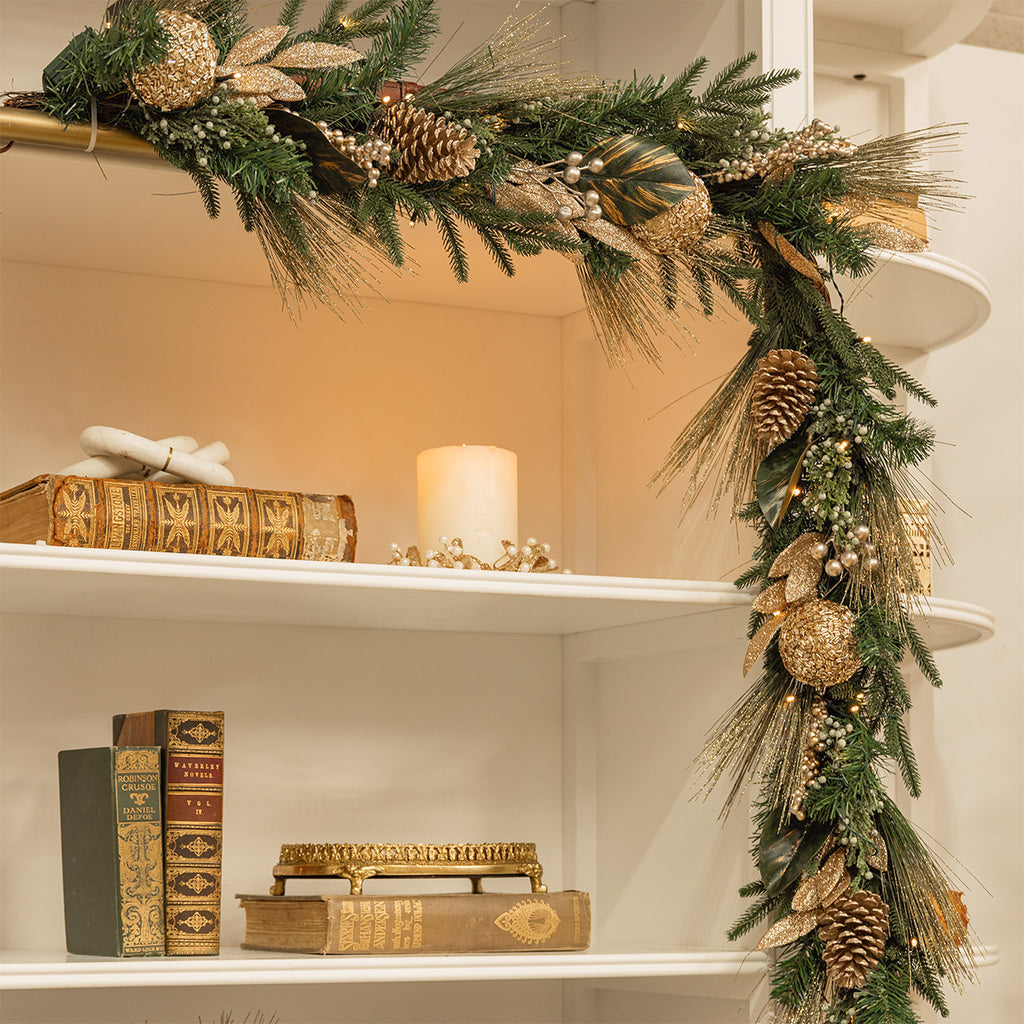 A champagne and green garland on a bookshelf.