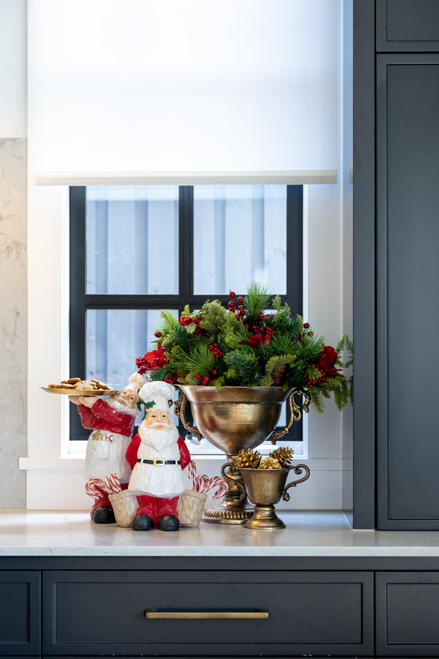 Decorative Christmas display on a kitchen counter with a large silver bowl, Santa figurine, and festive greenery.
