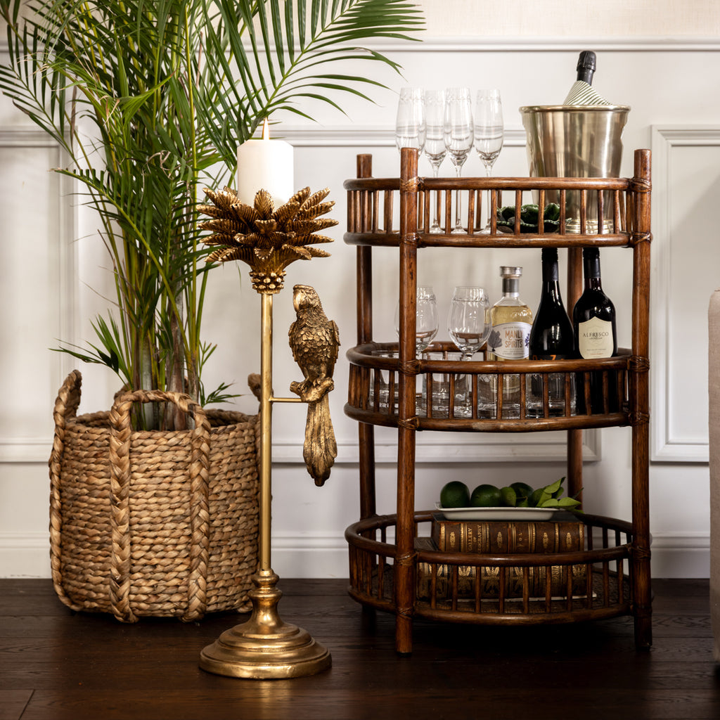 Majestic Parrot Candle Holder (Gold) Styled on Floor with Candle and Rattan Bar Behind
