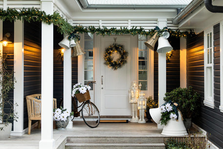 White bells on a porch with green foliage and poinsettia.