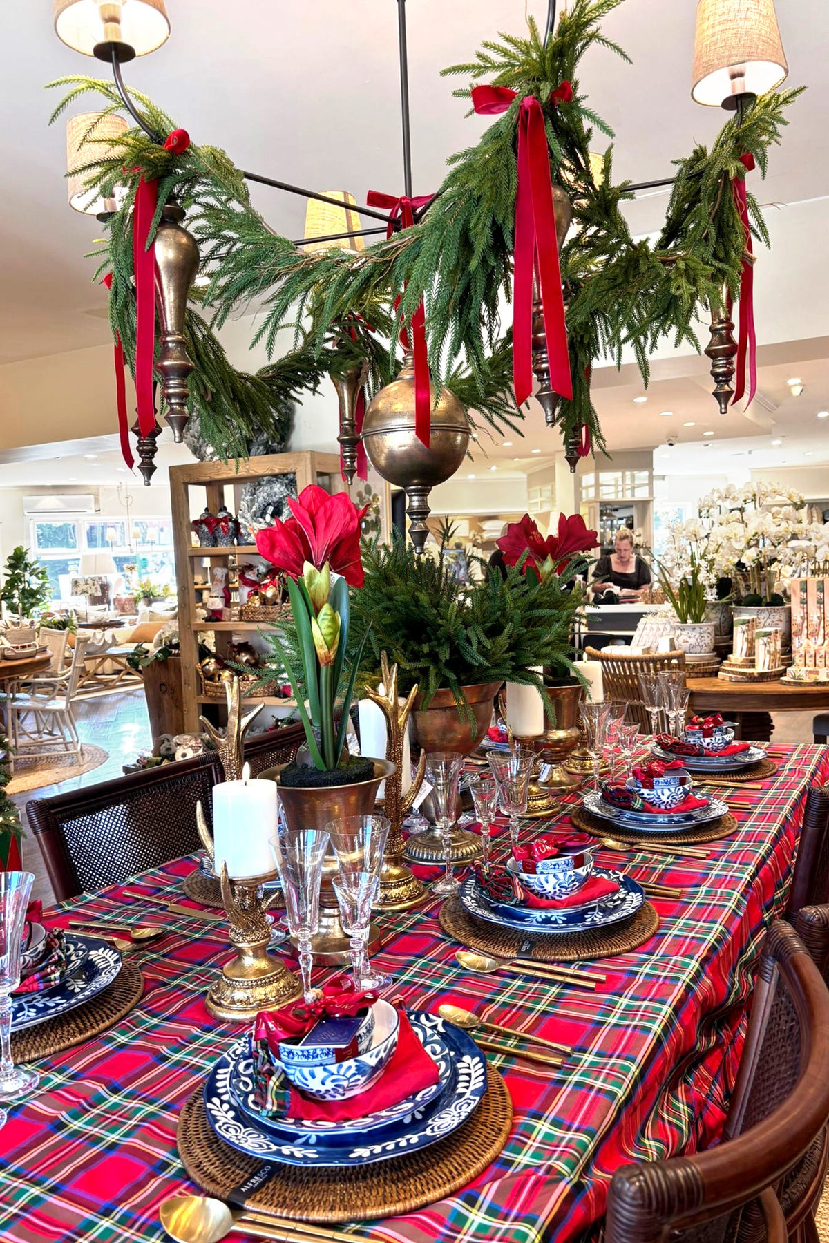 Decorative Christmas table setting with plaid tablecloth, candles, and greenery.