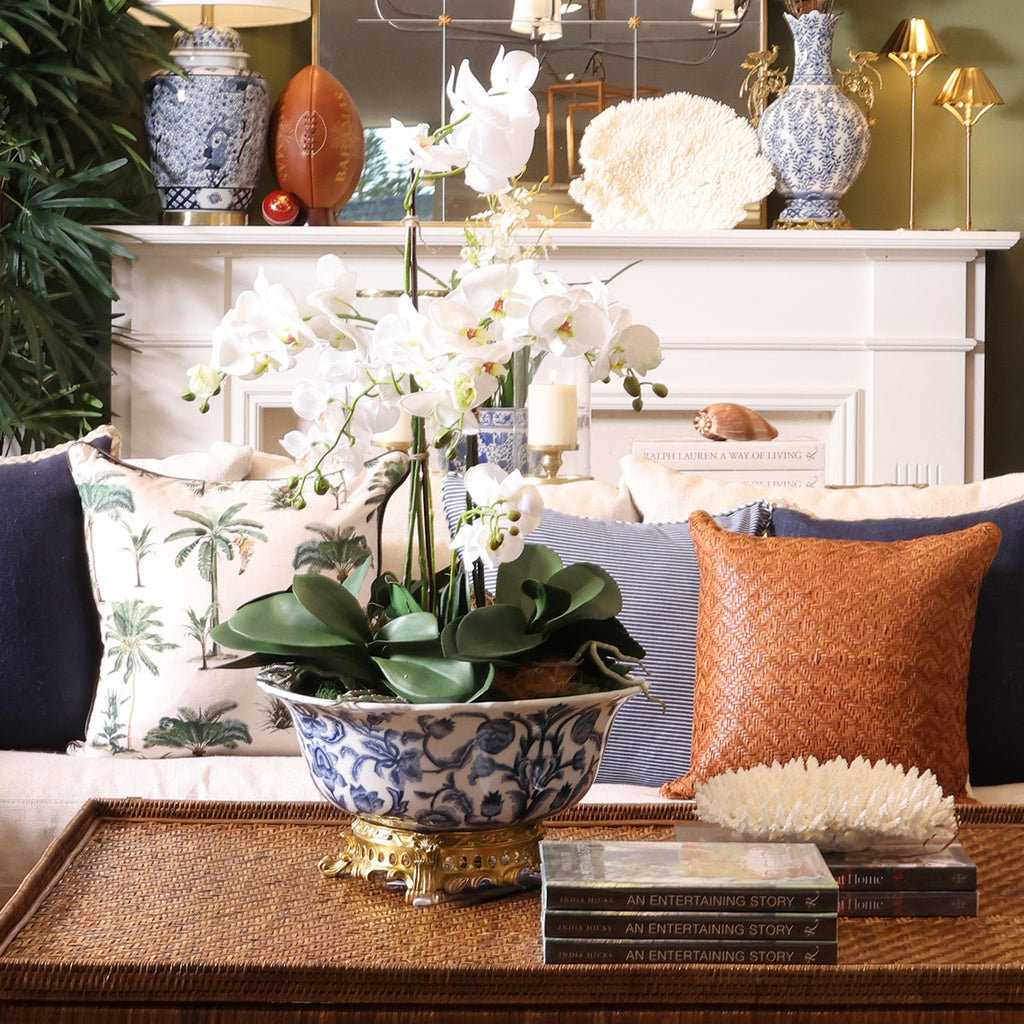 A styled interior scene with a blue-and-white ceramic planter holding white orchids.