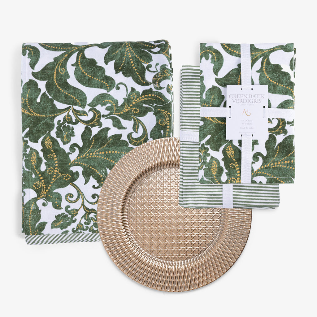 Green and gold damask patterned napkin and tablecloth, a green and white striped napkin, and a round woven-look gold placemat.
