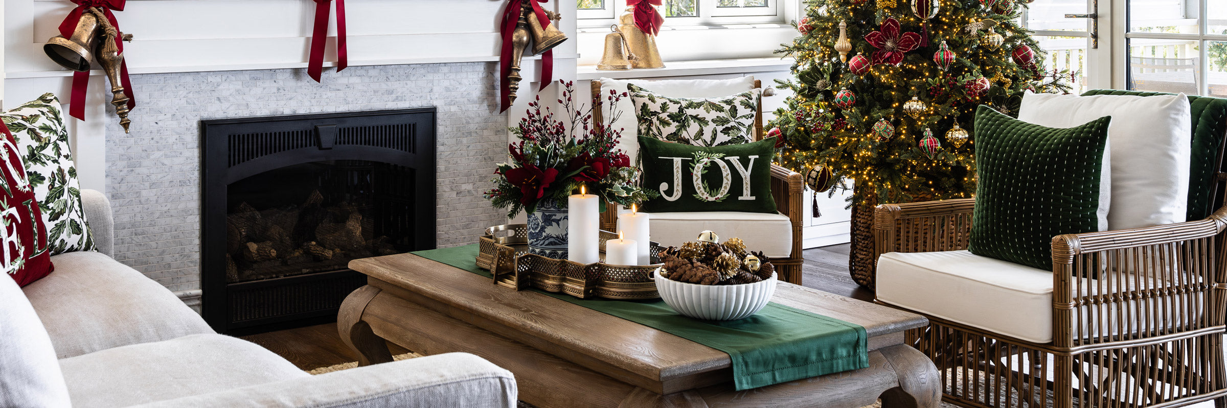 A Christmas living room with a green table runner, candles, amaryllis sprays, and velvet cushions.