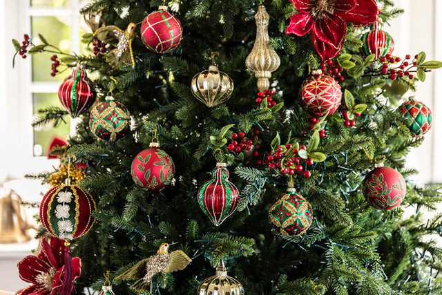 Red, green and gold baubles on a Christmas tree.