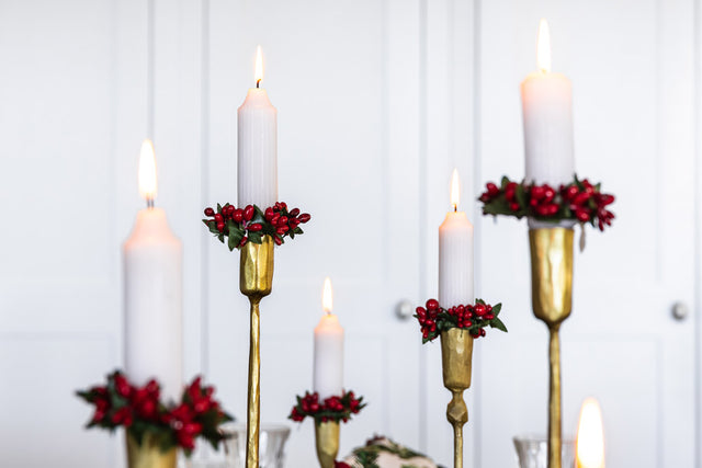 Rustic gold candle sticks with white taper candles and red berry candle rings.