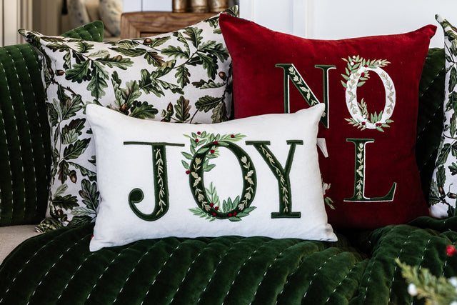 A group of velvet Christmas cushions sit on a green velvet throw.