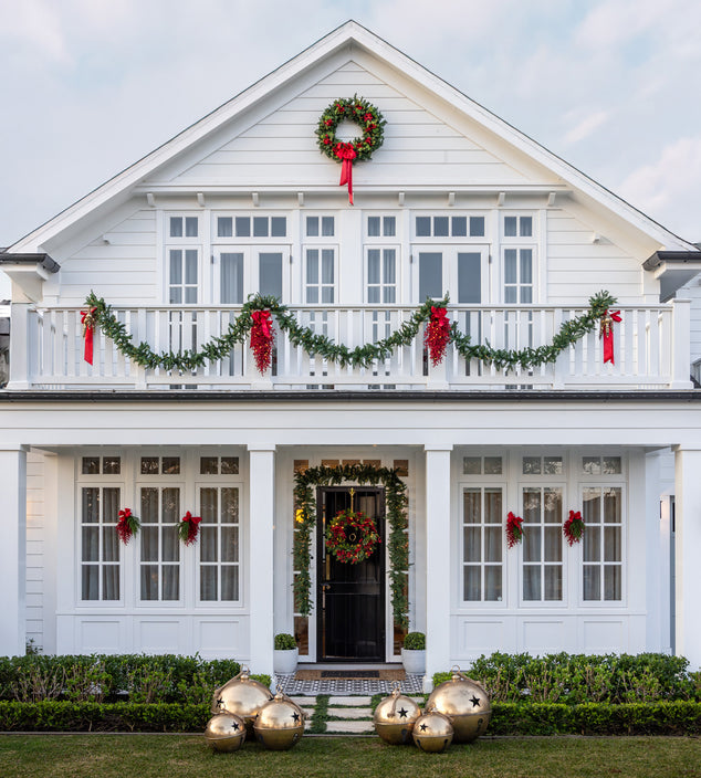 White house decorated with Christmas garlands, wreaths and giant gold bells.