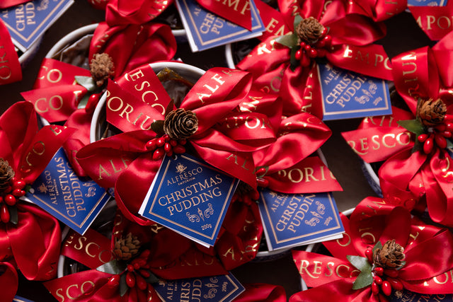 Lots of Christmas puddings tied with big red bows and pinecone-berry picks.