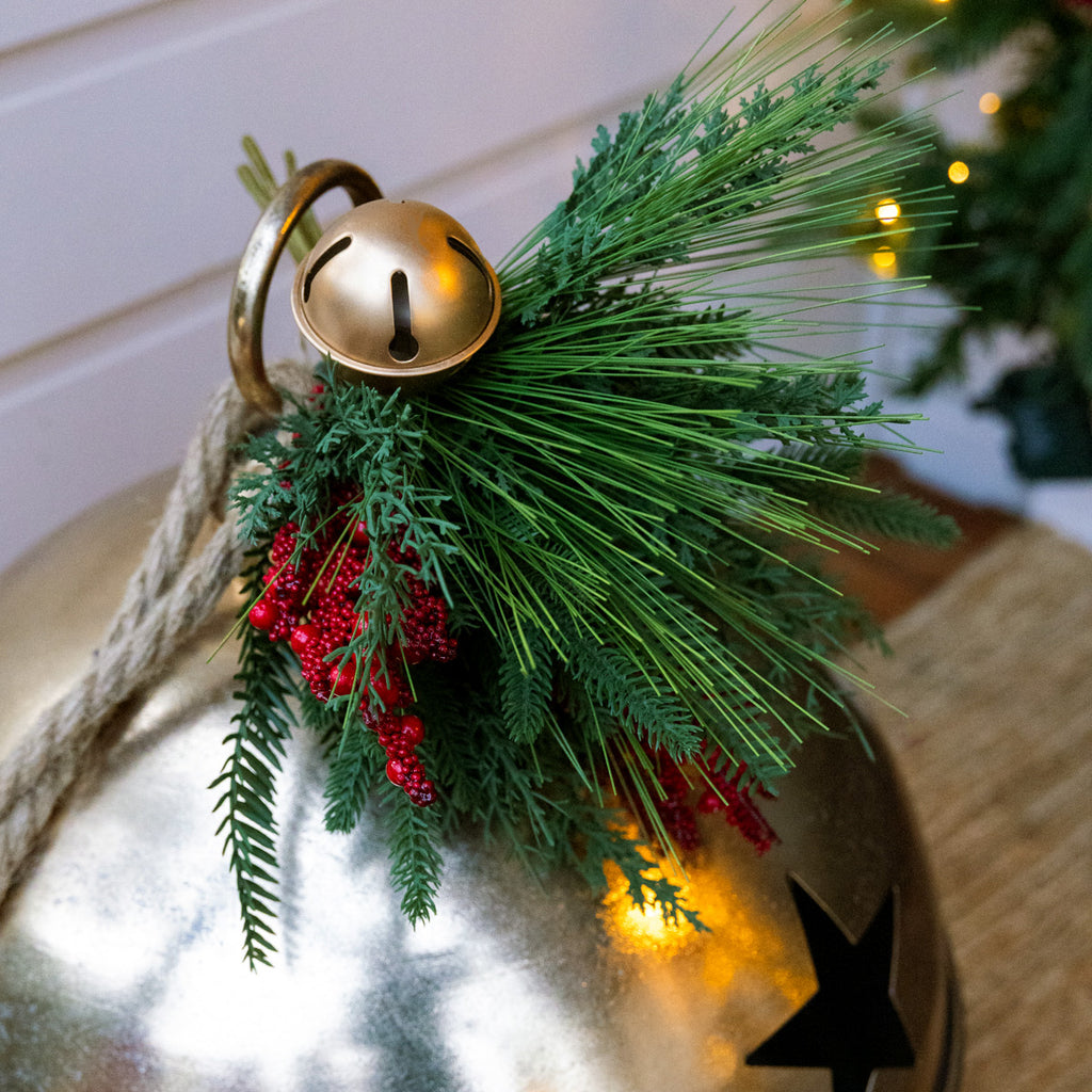 Decorative bell with greenery and red berries on a blurred background