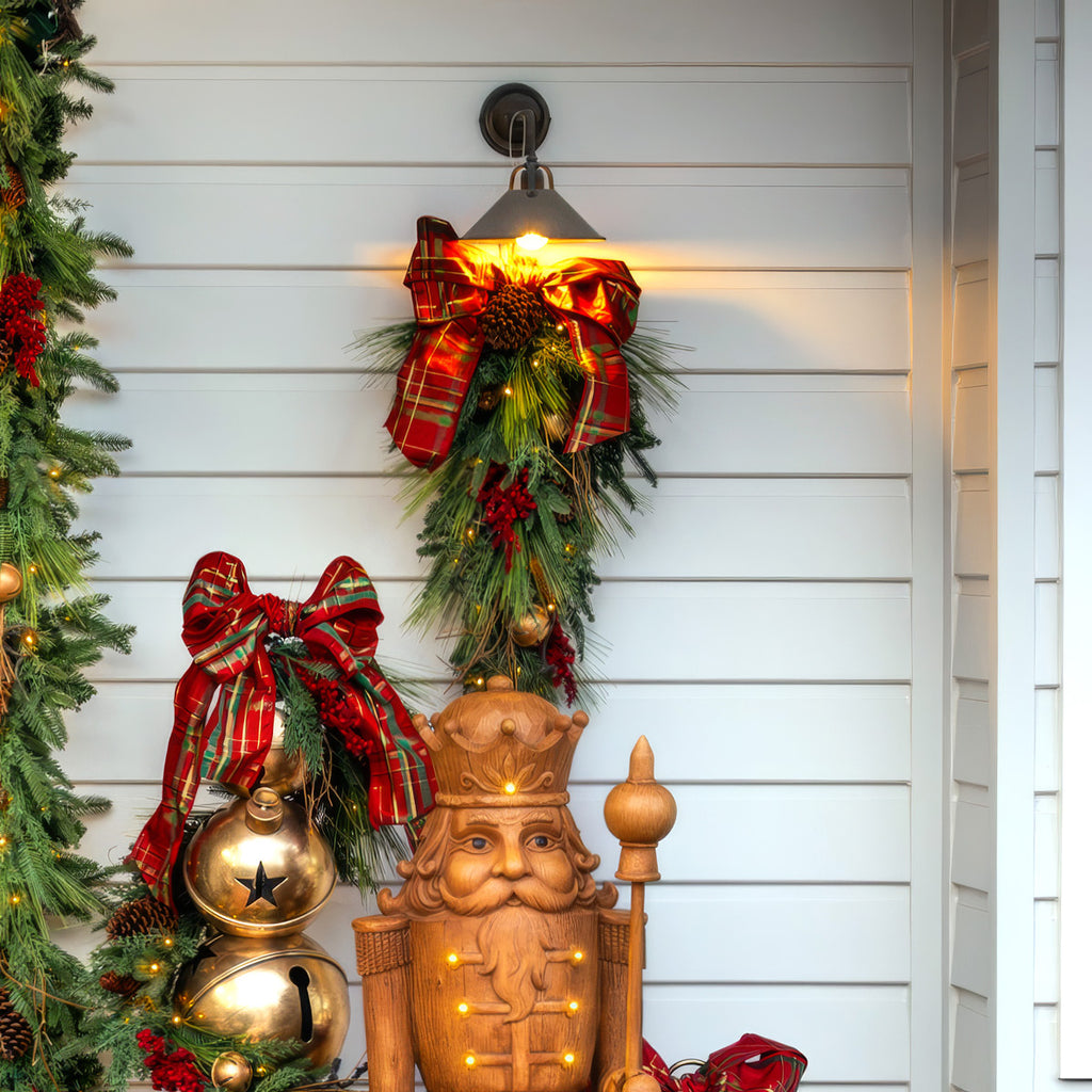 Decorative Christmas scene with a wooden Nutcracker, garlands, and lights on a white wall.