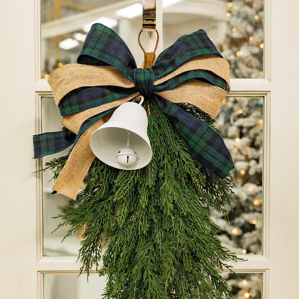 A green Christmas tear drop on a door decorated with tartan and hessian ribbon.