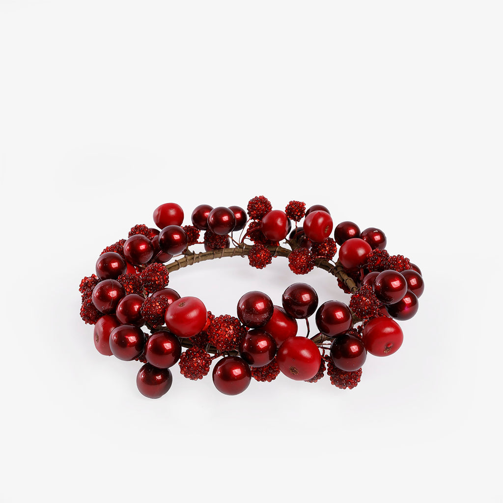 A decorative holiday candle wreath made of red berries and glossy red ornaments on a white background.