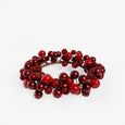 A decorative holiday candle wreath made of red berries and glossy red ornaments on a white background.