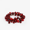 A decorative holiday candle wreath made of red berries and glossy red ornaments on a white background.