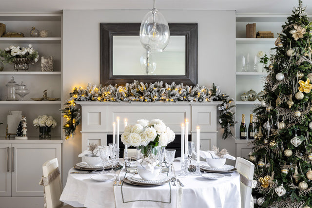 An elegant dining room complete with Christmas tree that features silver, white and champagne baubles.