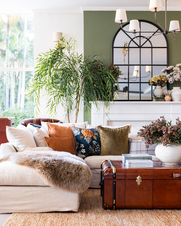 Living room with a beige sofa, decorative pillows, and a leather chest.
