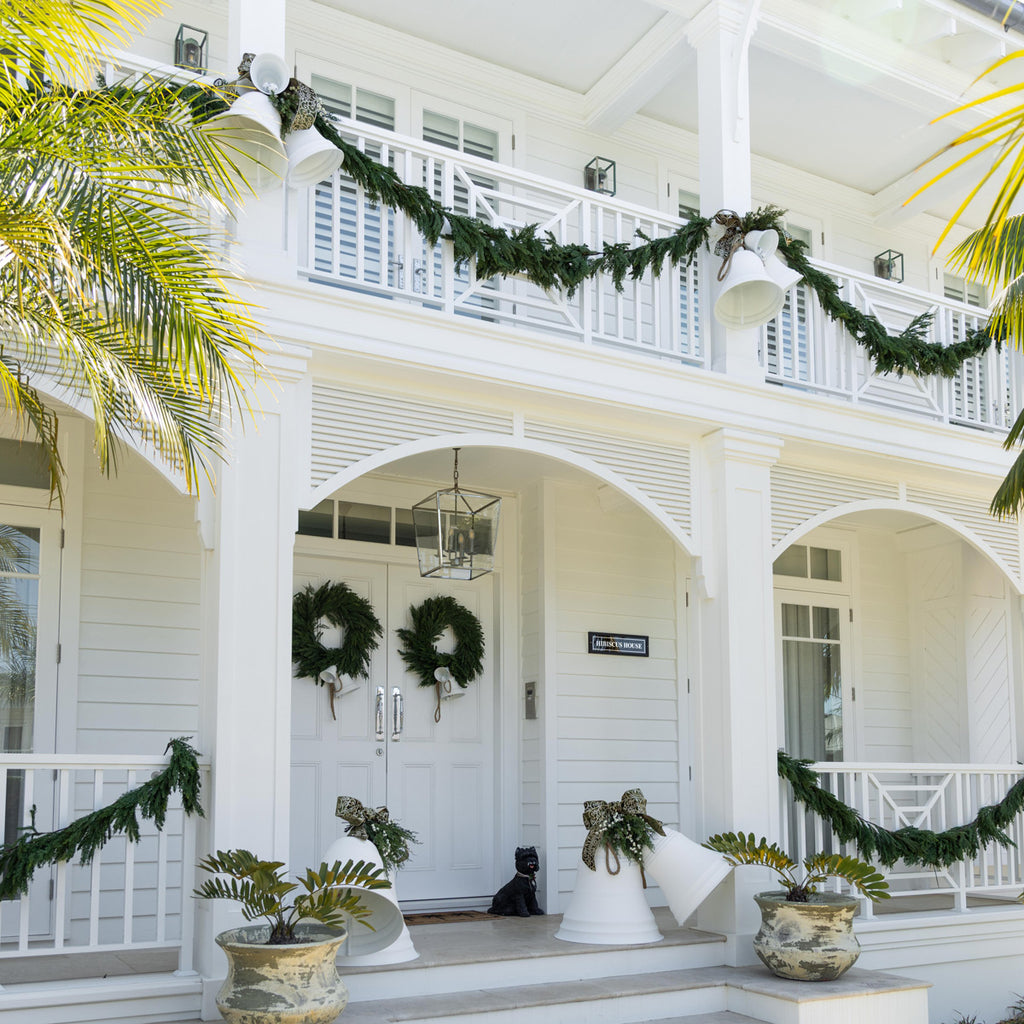 A white house decorated with white bells and green foliage.