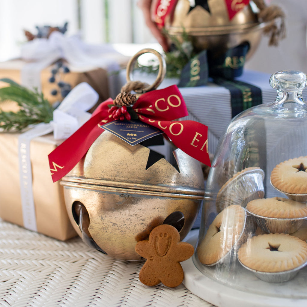 Gingerbread Men Star Bell Ornament on a coffee table with gifts and mince pies.