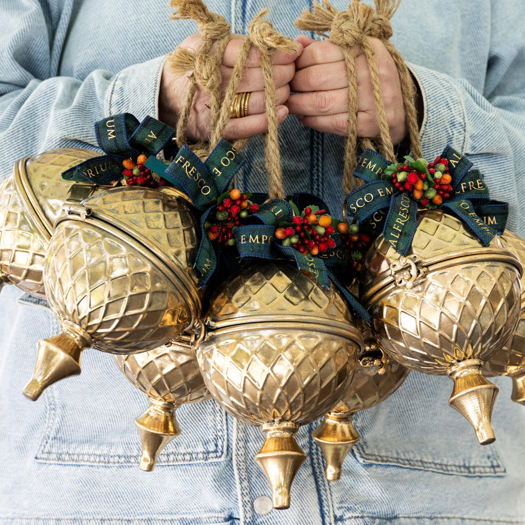 A person wearing a light blue denim jacket holds several gold gift baubles.
