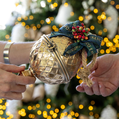 Gold Gift Bauble being handed between people.