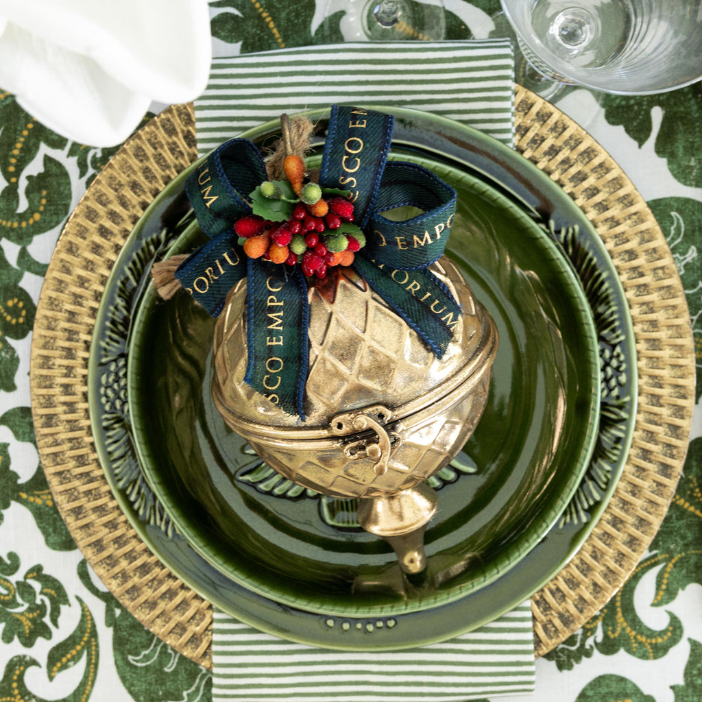 Gold Gift Bauble on green dinner plates.